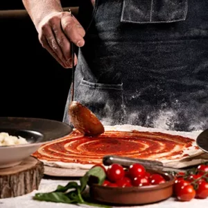 El chef Florin extendiendo tomate en pizza artesana restaurante italiano Fiori